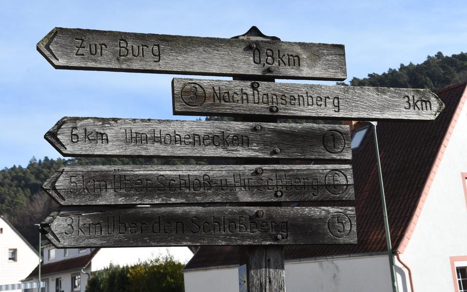 A weathered wooden sign in the village of Hohenecken points the way to the castle as well as other destinations along the forest's network of hiking trails south of Kaiserslautern, Germany.