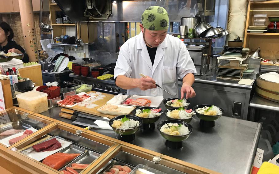 A chief prepares sashimi don, which are bowls of rice topped with fresh raw fish, at Sushidokoro Keiran restaurant in Sapporo's Nijo Market.