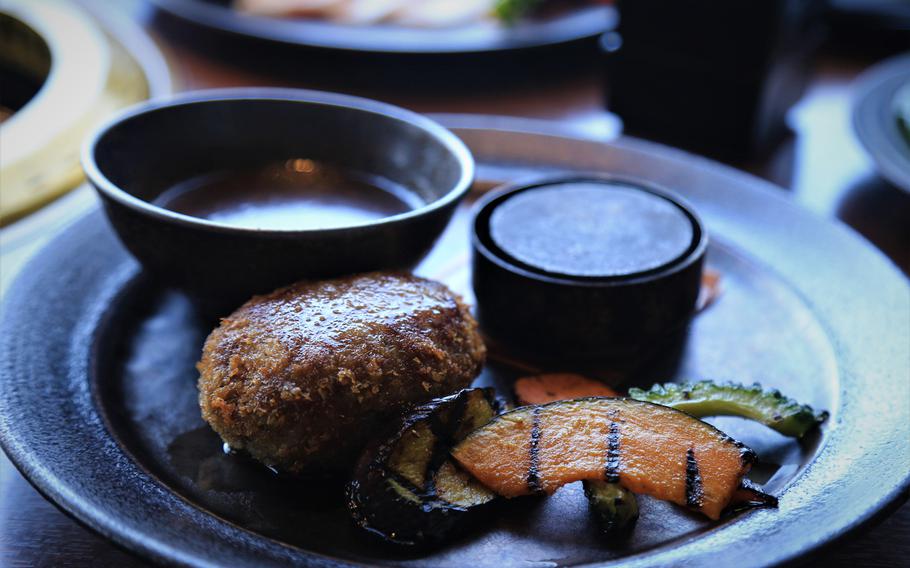 The hamburg steak is served on a hot stone plate that allows diners to cook the steak to their preference.