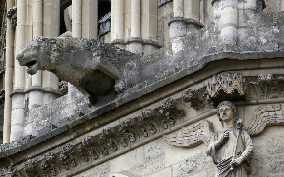 A lion-shaped gargoyle and an angel adorn the Cathedral of Notre-Dame in Reims, France.