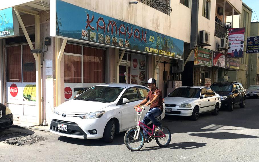 A local man rides a bike past a Filipino restaurant in Qudaibiya, Bahrain.
