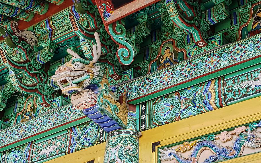 Upon arriving at the entrance of Mangisa Temple, visitors pass through a gate decorated with intricate wooden carvings of dragons. 