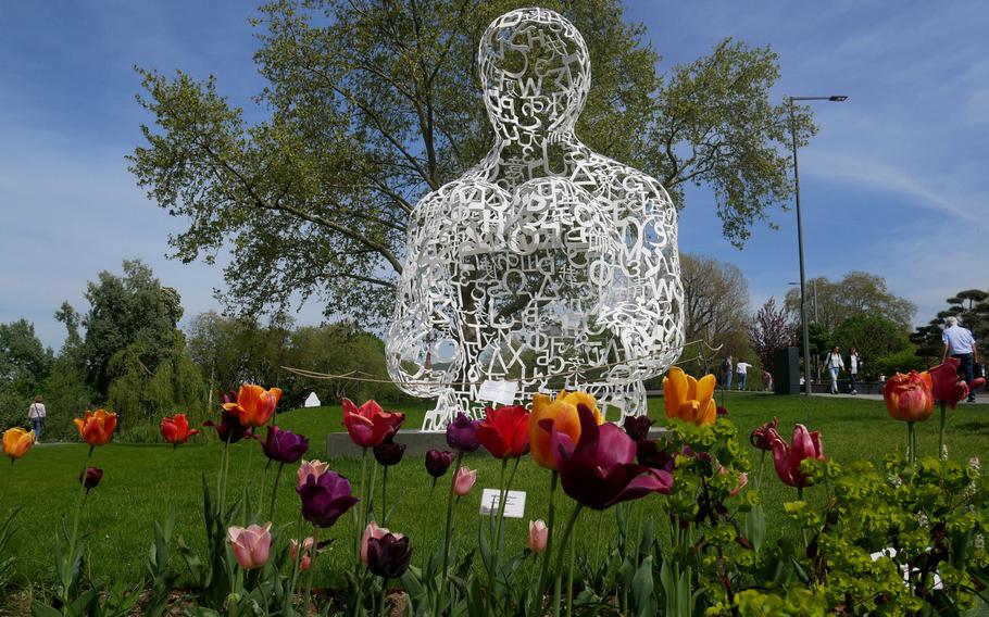 A sculpture by Jaume Plensa, made of painted steel, sits among the flowers at the Budesgartenschau in Heilbronn, Germany. There are many works of art sprinkled throughout the grounds of the federal garden show.