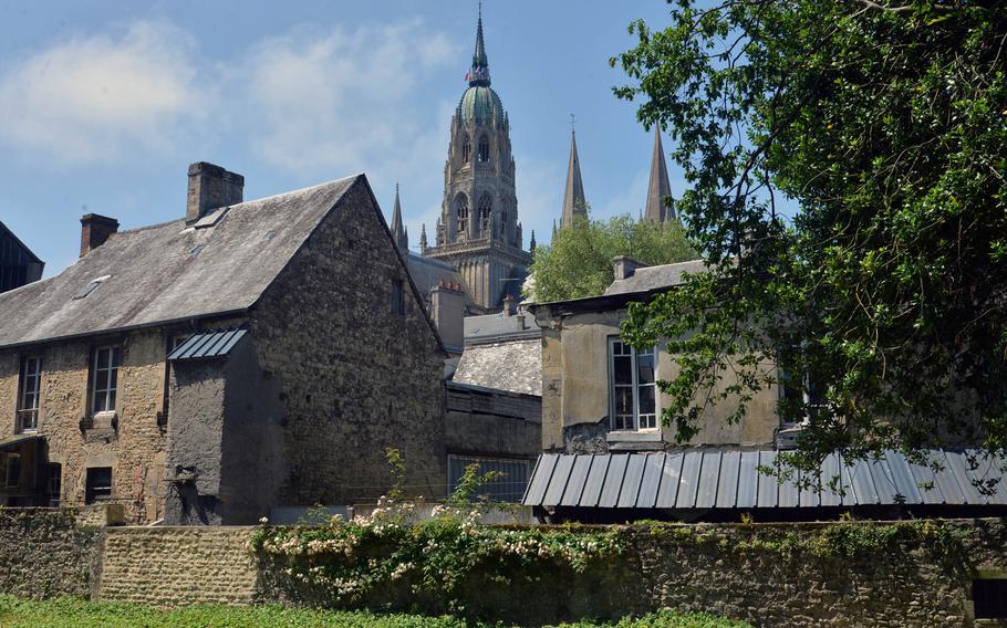 The 13th century Notre Dame Cathedral in Bayeux, France, towers over the streets of the city, as seen from a peaceful park.
