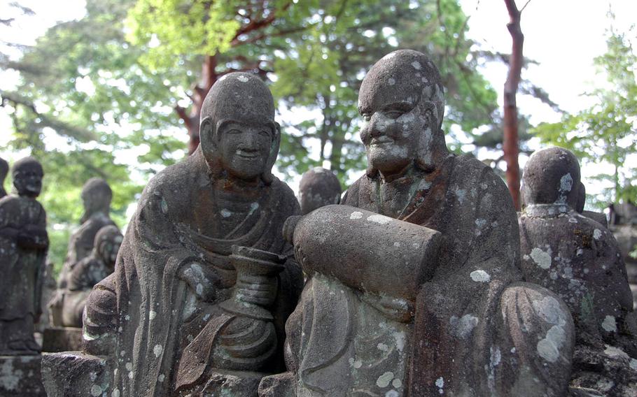 Two disciples of Buddha share a jug in the 500 Rakan compound at Kitain temple, Kawagoe, Japan, on May 18, 2019.
