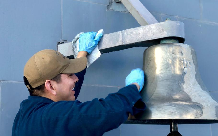 Petty Officer 1st Class Humberto Vargas, a culinary specialist assigned to the USS Antietam, shines the ship's bell on Friday, May 24, 2019.