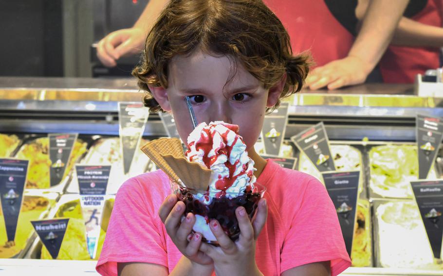 Cecelia Pinson, 7, stares at a mixed berry ice cream sundae she's holding in front of the display of more than 30 varieties of ice cream at Palazzo Sandro in Kaiserslautern, Germany, on July 22. Palazzo Sandro has a sundae happy hour after 7 p.m.
