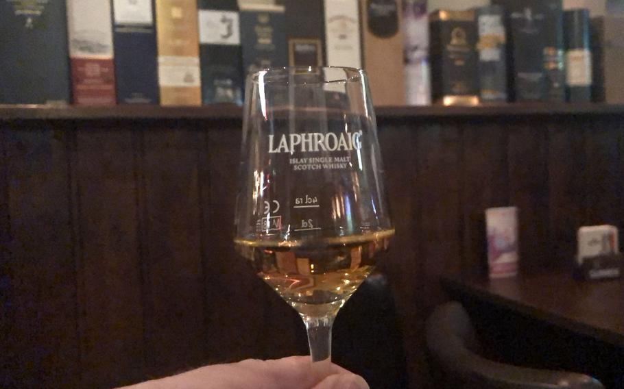 A dram of Laphroaig Triple Wood Scotch whisky at Scotch N Soda in Wiesbaden, Germany. Note the boxes of whiskies and whiskeys lining the wall. The gastropub offers more than 200 different varieties of the drink.