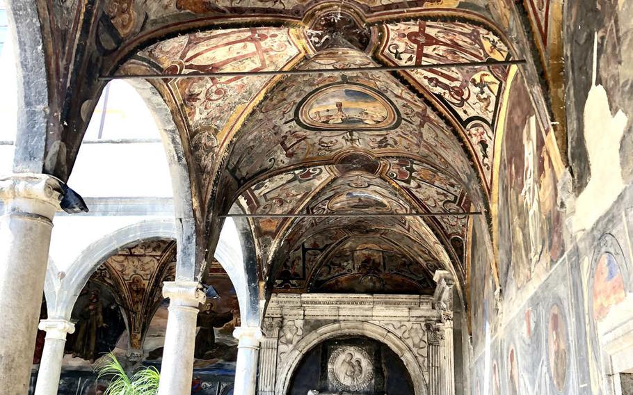 Gaudy ceiling murals lead to what could be Dracula's tomb in  the corner of a cloister at the Church of Santa Maria la Nova in Naples, Italy.
