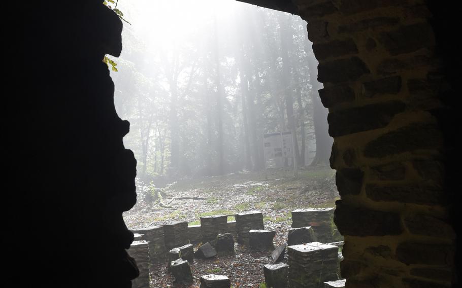 A misty forest and stone seats can be seen through an opening in a stone building inside the ancient Celtic ring wall in Otzenhausen, Germany.