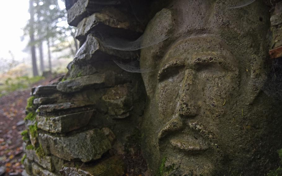 A stone face is carved into the rock next to an ancient spring inside the Celtic ring wall in Otzenhausen, Germany.