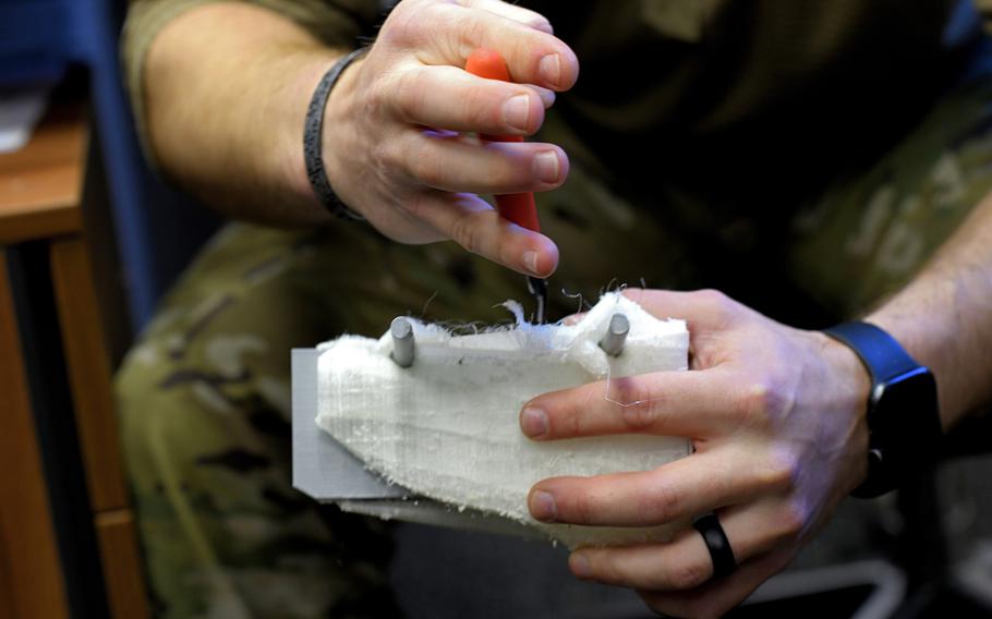 Staff Sgt. William Riddle, a 48th Civil Engineer Squadron Explosive Ordnance Disposal NCO, carves dry molding off of a recently printed training aid at Royal Air Force Lakenheath, England, Nov. 19, 2019.