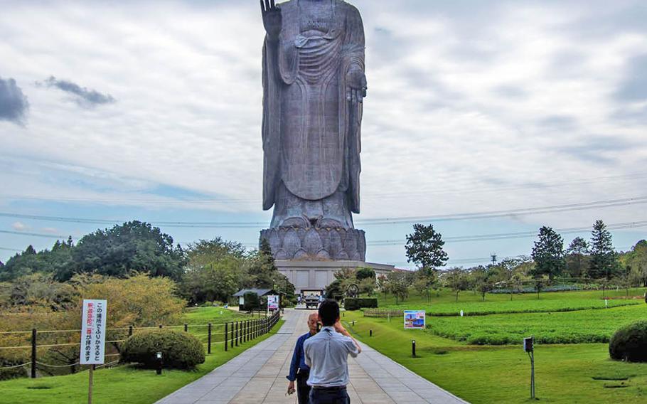 Tourists pose in front of Japan???s tallest bronze Buddha statue in Ibaraki prefecture, Sept.18, 2019.