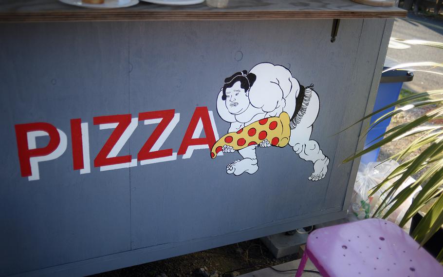 A sumo wrestler serves as the mascot for Dosukoi Pizza at Delta East in Fussa, Japan. "Dosukoi!" is a word they often shout to pump themselves up for a match.