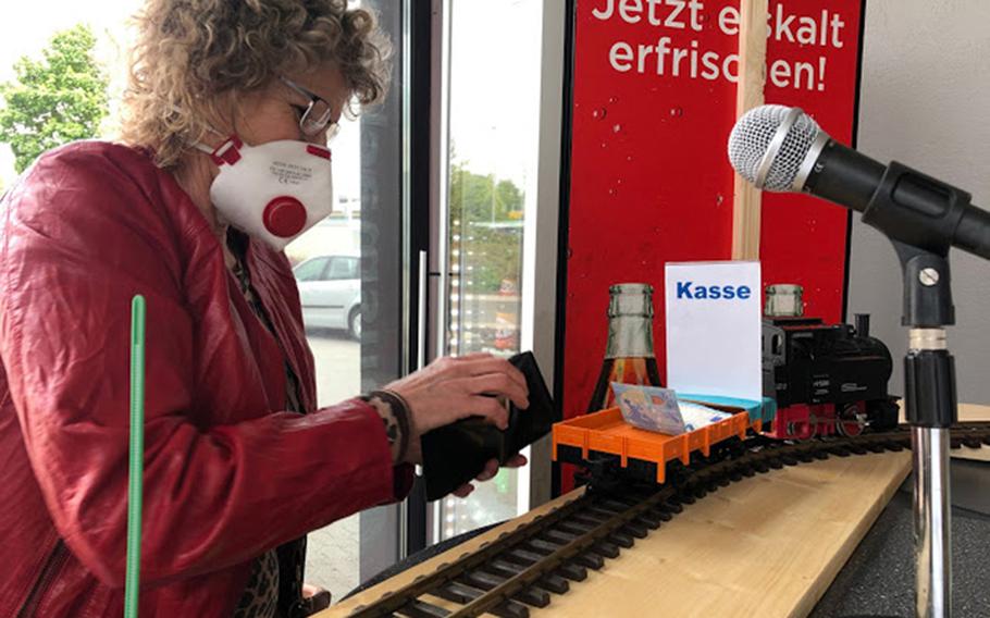 A customer places money in the model train that shuttles between the cashier and clients at Der Fleischerimbiss in Kirchheimbolanden, Germany, on April 30, 2020. The snack bar's owner, Mario Ludwig, set up two trains to allow him to keep his business open while maintaining a healthy social distance from customers to help in the fight against the coronavirus.