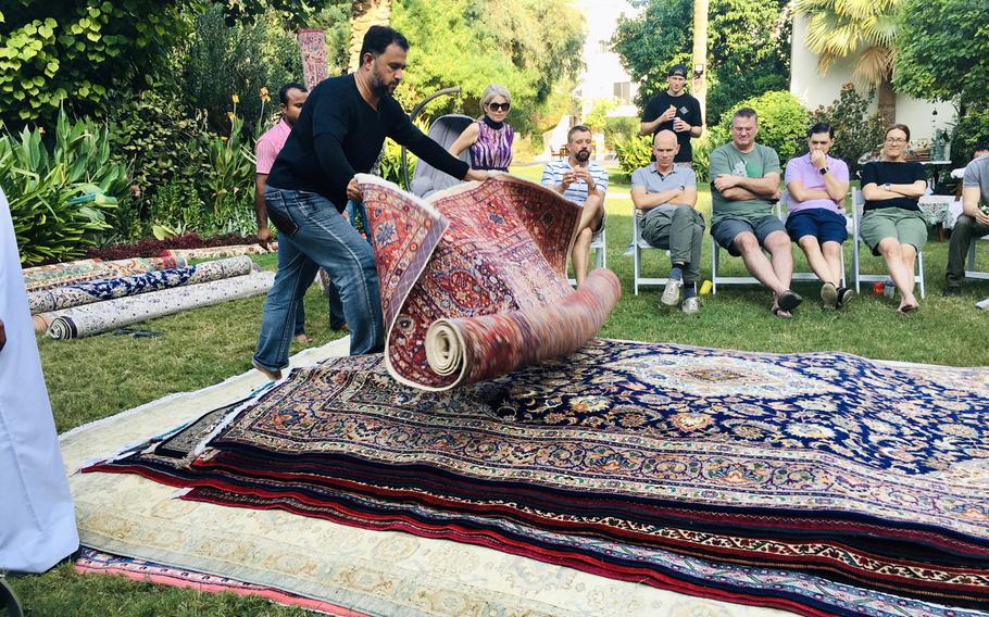 Mustafa Ameen, from the Carpet House in Adliya, Bahrain, rolls out a carpet during a ''rug flop'' event hosted by U.S. Navy Cmdr. Joe Zerby and his wife, Jill.