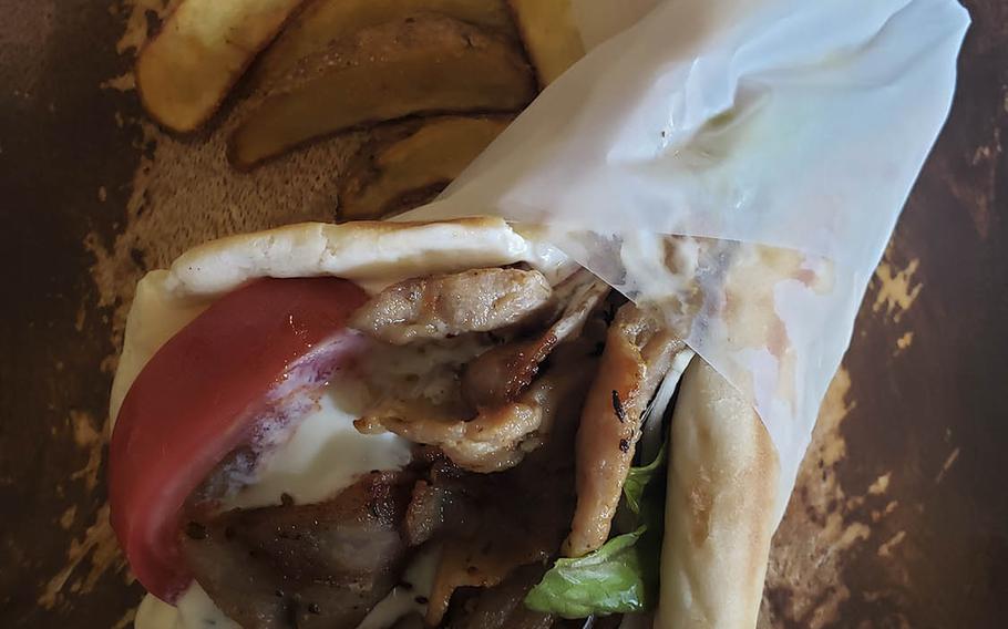 The pork gyro from Shupoul in Tachikawa, Japan: A tightly wrapped pita stuffed with sliced pork, tomato, red onion and Greek yoghurt sitting next to a stack of freshly fried, lightly salted potatoes.