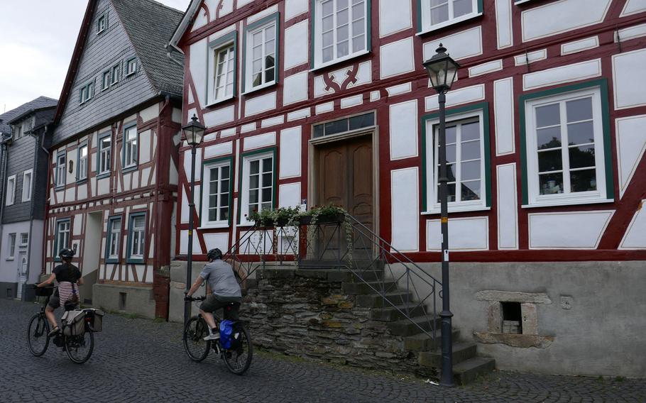 A pair of bicyclists pass by two half-timbered houses on an old cobblestone street in Kastellaun. Although the town and the countryside are quite hilly, it's still popular for cycling and hiking in Germany's Hunsrueck region.