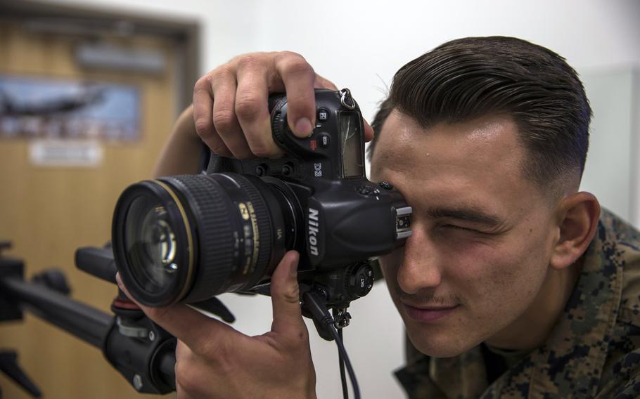 U.S. Marine Corps Lance Cpl. John Hall, a combat photographer, takes a picture in the promotion photo studio at  Marine Corps Air Station in Yuma, Ariz., in June 2019. In a move to fight racial and gender bias, photos will no longer be used by promotion boards or in the selection process for opportunities such as training and assignments, the Marine Corps has said.