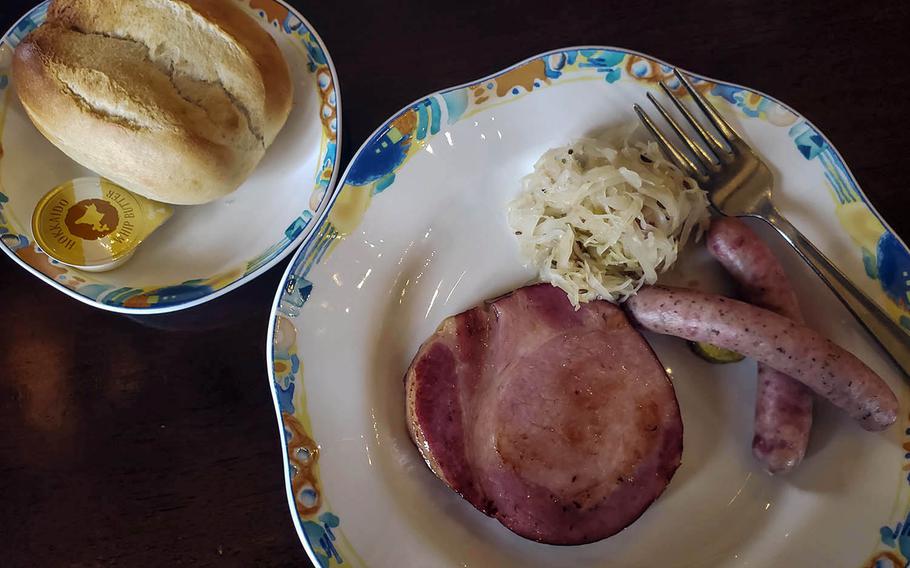 The ham steak meal set from Stuben Ohtama in Fussa, Japan, included a fresh-baked roll and the main dish of two small sausages, a small but thick ham steak and a serving of sauerkraut. 