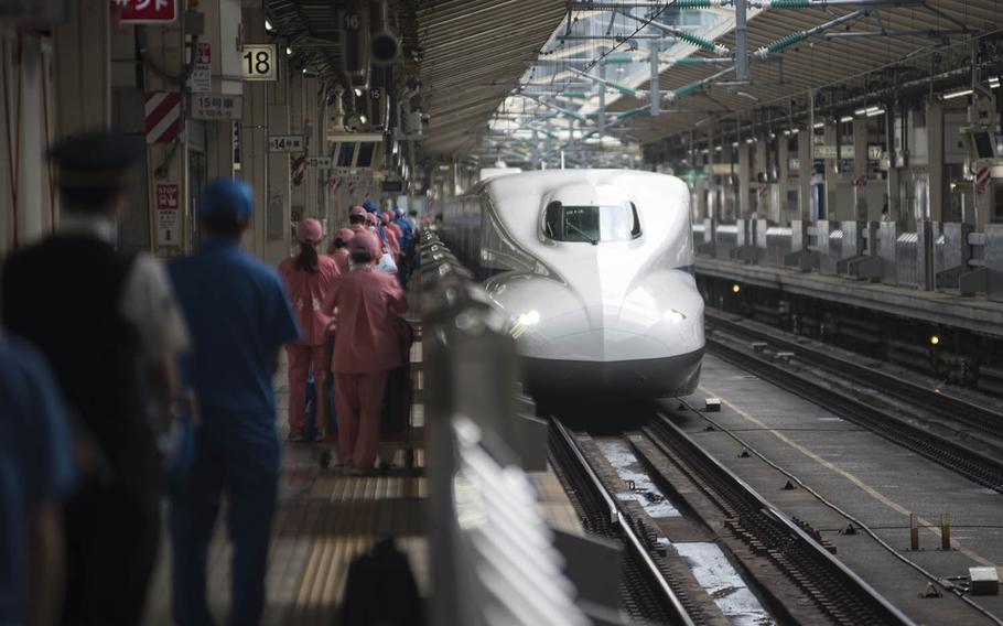 Shinkansen conductor and cleaning staff, wearing the pink uniforms, wait to board an incoming bullet train at Tokyo Station, Sept. 3, 2020. The trains can reach speeds of nearly 200 mph and are lauded as a fast, convenient way to travel throughout Japan.