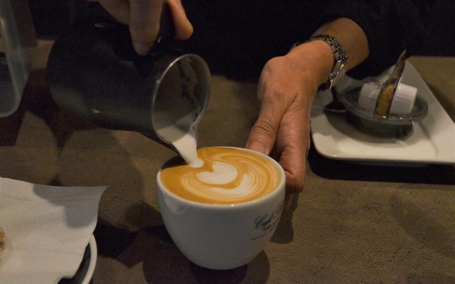 A barista at Cafe Plaisir in Saarlouis, Germany, pours steamed milk onto espresso coffee to make a cappuccino on Oct. 17, 2020. Cafe Plaisir sources coffee beans from farms around the world and roasts its own coffee.