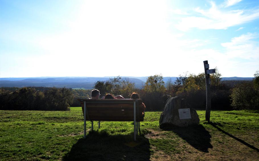 A family relaxes on a sunbathing bench looking toward France, near the trailhead of the Alte Grenzweg in Berus, Germany on Oct. 30, 2020. The lightly trafficked 4.2-mile loop of the trail that crisscrosses in and out of France is ideal for those seeking fresh air and exercise as Germany and France toughen up coronavirus restrictions.