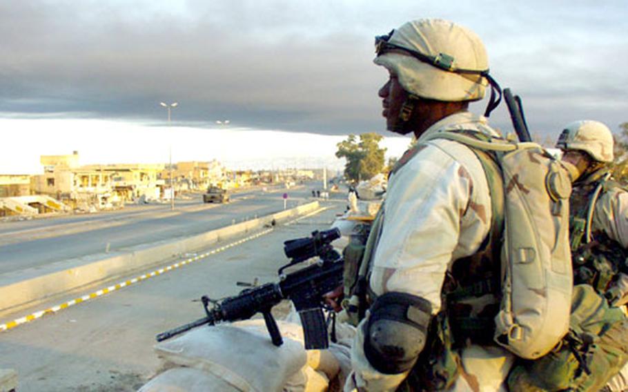 Under a sooty cloud from a nearby oil refinery, Sgt. Melvin Davis, 32, of Battery B, Task Force 1-7, surveys the empty main street of Bayji, Iraq.
