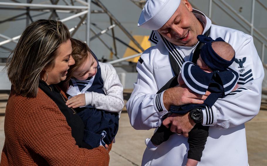 Corey Mink (right) holds 3-month-old daughter Charlotte for the first time as wife Julie and daughter Olivia, 4, welcome him home in time for the holidays at Naval Station Mayport on Nov. 24, 2021.