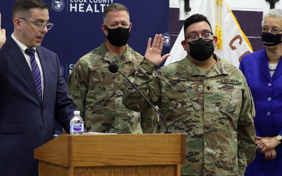 Kevin Riddle, left, Chicago field office director for U.S. Citizenship and Immigration Services, asks Illinois National Guard Spec. Alan Juarez, second from right, to recite the oath of allegiance in a special ceremony at Cook County Health’s vaccination site at Thornton Township High School in Harvey on June 10, 2021. Major Gen. Richard Neely, adjutant general of the state of Illinois and Cook County Board President Toni Preckwinkle were on hand..