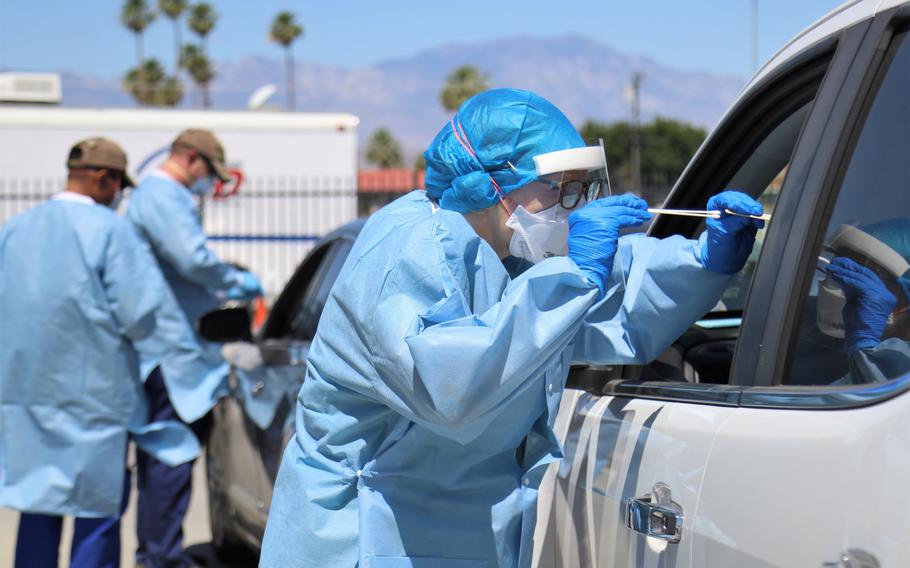 Marcie Richmond, a physician with California Medical Assistance Team, administers a COVID-19 test to a patient at a drive-thru testing site in Indio, Calif., May 19, 2020.