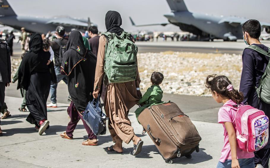 In this Aug. 24, 2021, file photo, provided by the U.S. Marine Corps, families walk towards their flight during ongoing evacuations at Hamid Karzai International Airport, in Kabul, Afghanistan. 
