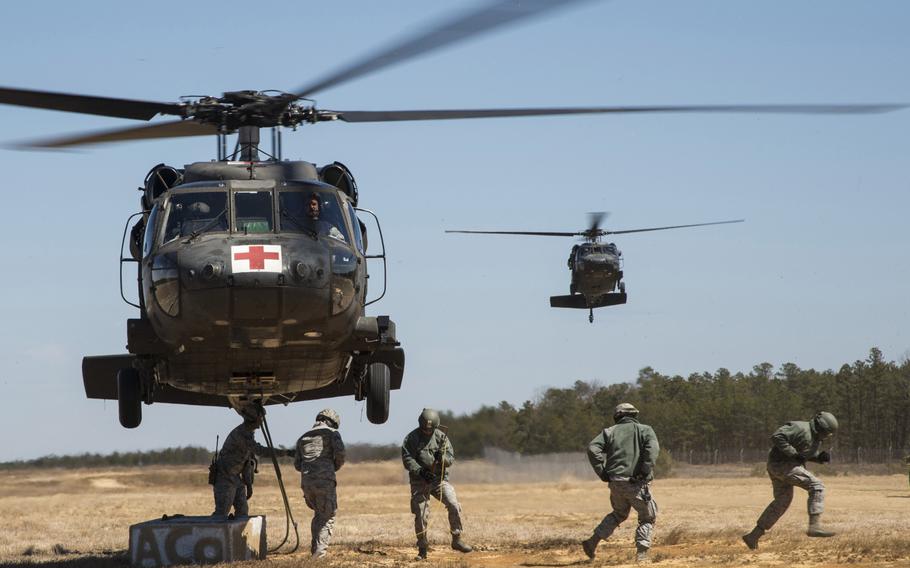 Airmen from the 621st Contingency Response Wing run away from a U.S. Army UH-60 Black Hawk helicopter assigned to the 1-150th Assault Helicopter Battalion after hooking up cargo, as another Black Hawk waits for its turn during sling-load training at Joint Base McGuire-Dix-Lakehurst, N.J., on Wednesday, April 1, 2015.