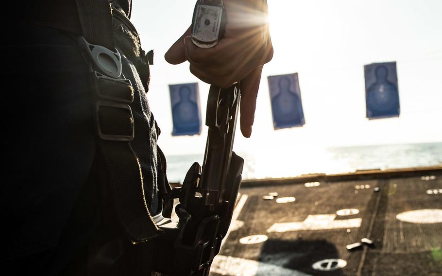 A sailor draws an M9 service pistol from his holster during a gun shoot on the flight deck of the guided-missile destroyer USS Farragut in the Gulf of Oman on Dec. 13, 2019.