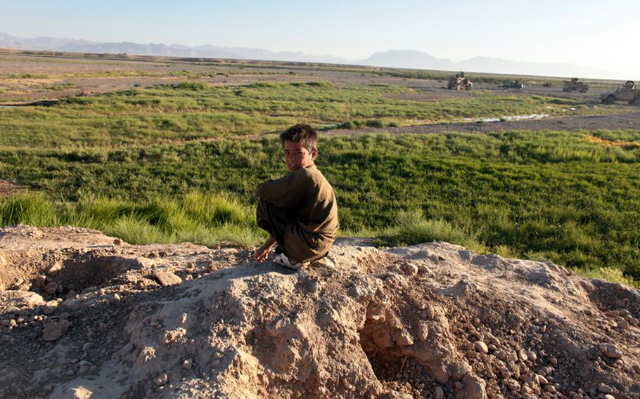 A boy watches quietly as an early morning patrol of Afghan police and U.S. soldiers from Troop C, 4th Squadron, 73rd Cavalry Regiment pass by in Bala Baluk district, Farah province, Afghanistan.