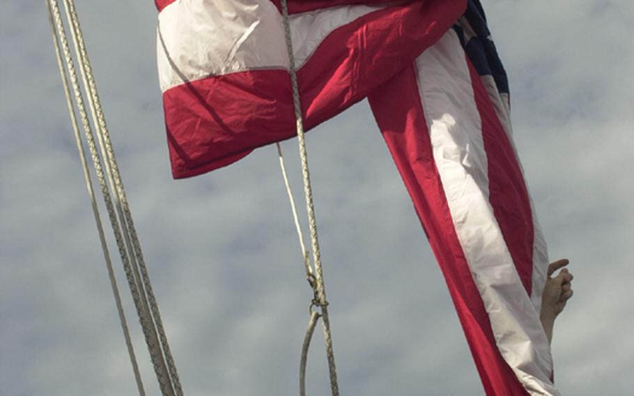 A crewman aboard the USS George Washington raises the American flag as the aircraft carrier prepares to leave Pusan, South Korea, on Sunday at the start of the Invincible Spirit military exercise east of the Korean Peninsula.  