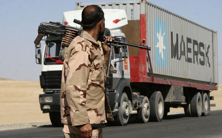 A private security contractor watches a NATO supply truck drive past in Ghazni province, southwest of Kabul in October.