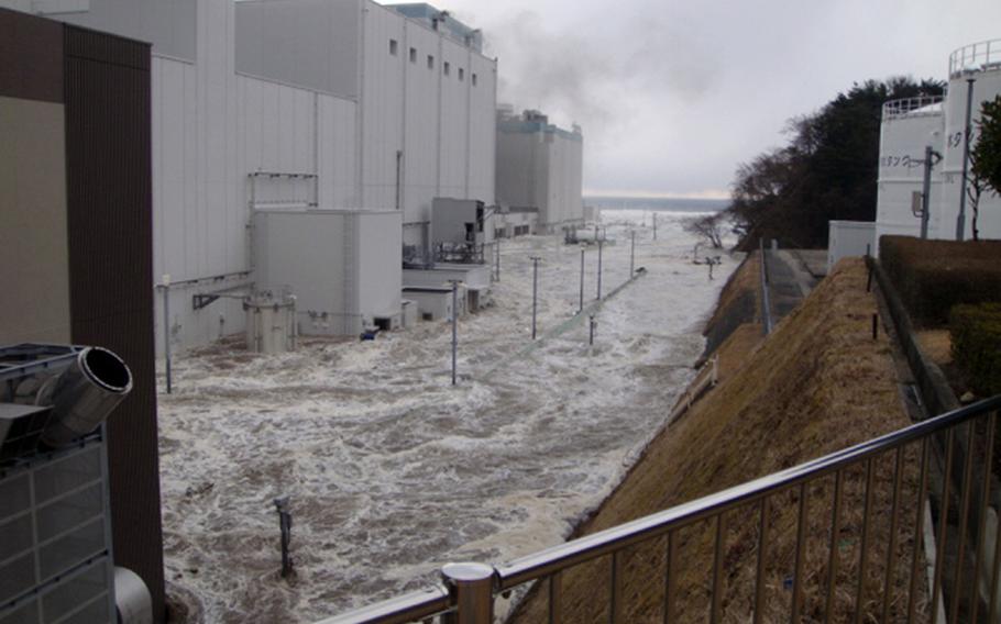 In this March 11, 2011 photo released by Tokyo Electric Power Co. (TEPCO), the access road at the compound of the Fukushima Dai-ichi nuclear power plant is flooded as a tsunami hit the facility following a massive earthquake in Okuma town, Fukushima Prefecture, northeastern Japan. 