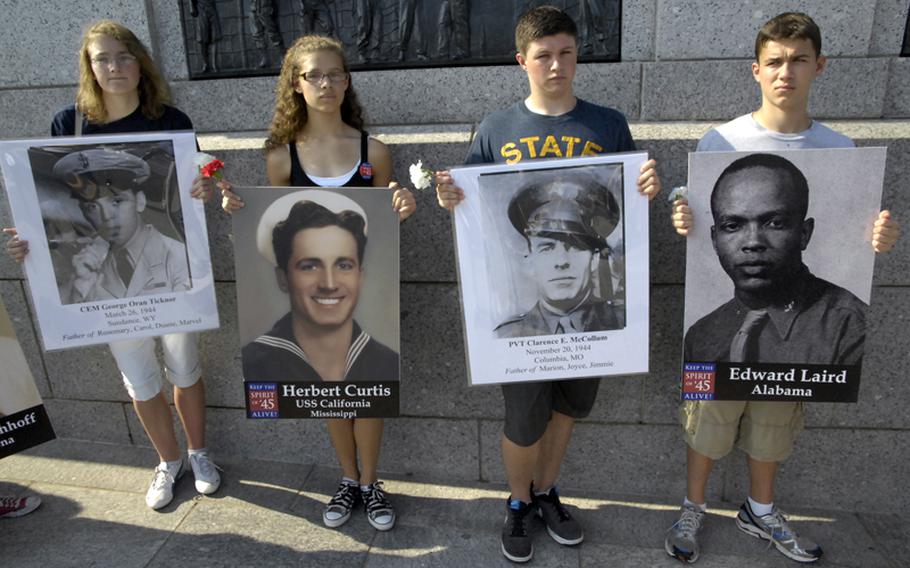 The youngest generation carries photos of fallen members of the Greatest Generation at Monday's ceremony at the National World War II Memorial.