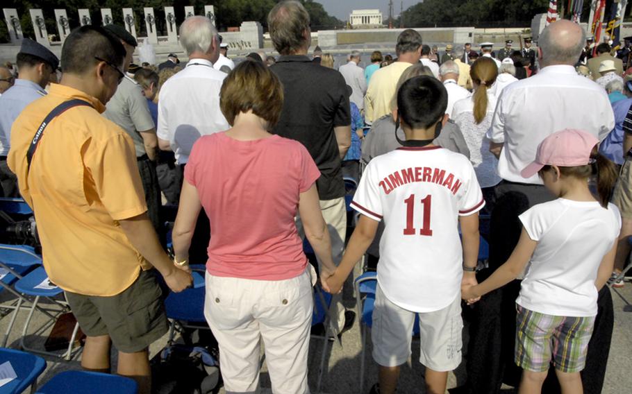 A family listens to the invocation during Monday's ceremony at the National World War II Memorial.