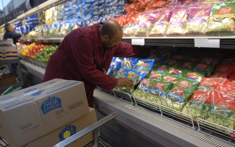 Garry Briggs, a store worker leader for the commissary at Ramstein Air Base, Germany, fills shelves Wednesday with bags of lettuce airlifted from the States.