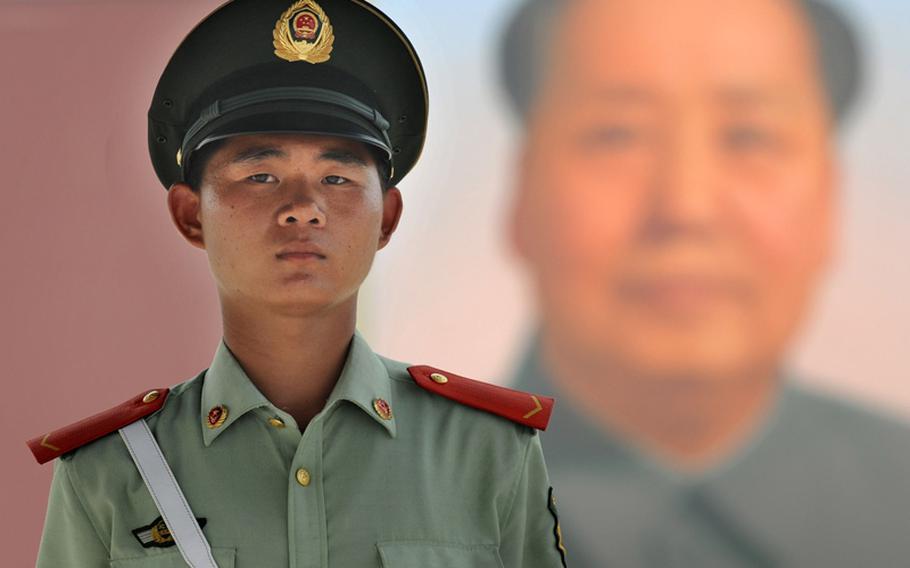 A young Chinese soldier stands at his post under the watchful gaze of Mao Tse Tung at Beijing's Tiananmen Square, August 3, 2008.