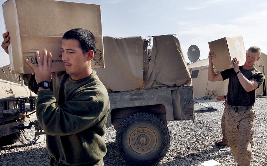 Navy Hospitalman Michael Nakamura, left, and Marine Lance Corp. Tyler Turlington, of Jacksonville, North Carolina, carry boxes of supplies to the mess area of the remote FOB Hassanabad, Afghanistan, during a re-supply session in 2009.