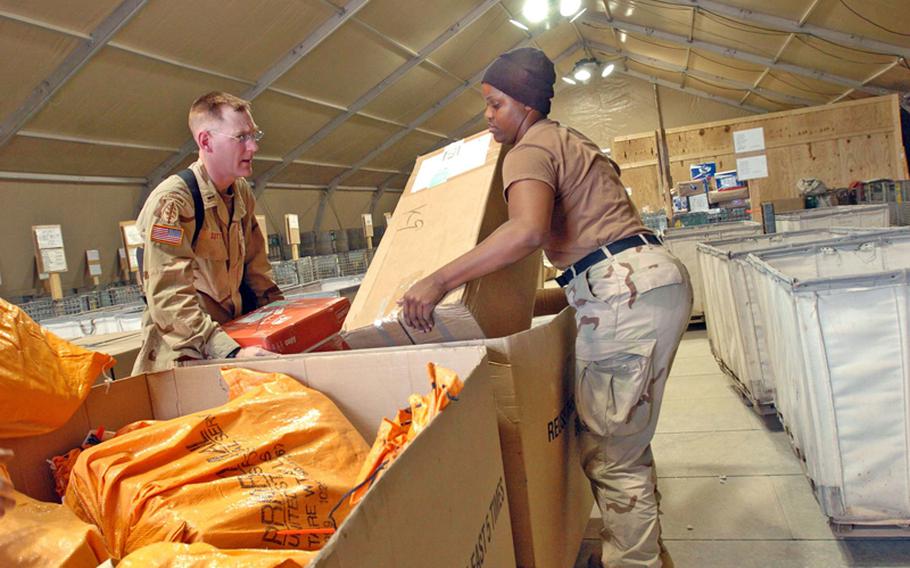 1st Lt. Paul Sutton, left, and Spc. Summer Meadows, both of 394th Adjutant General Company (Postal), sort the mail in the designated unit bins at LSA Anaconda, Iraq, in 2005.