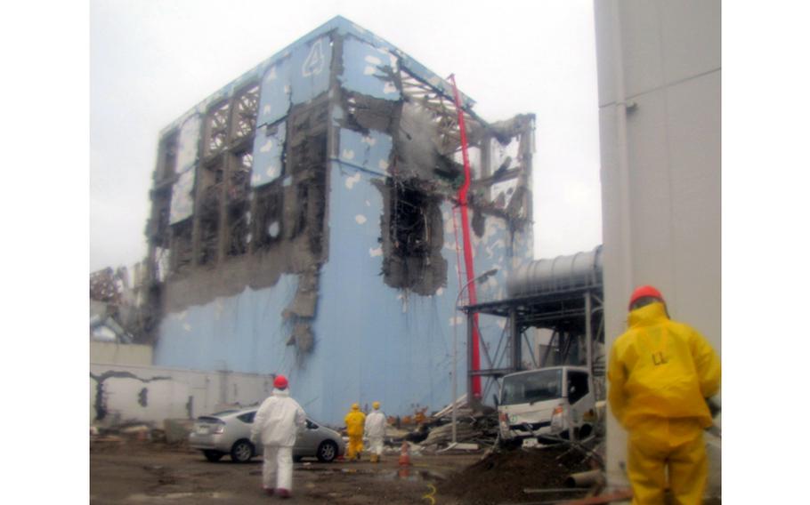 In this March 22, 2011 file photo released by Tokyo Electric Power Co. (TEPCO) , workers in protective suits conduct cooling operation by spraying water at the damaged No. 4 unit of the Fukushima Dai-ichi nuclear complex in Okumamachi, northeastern Japan.