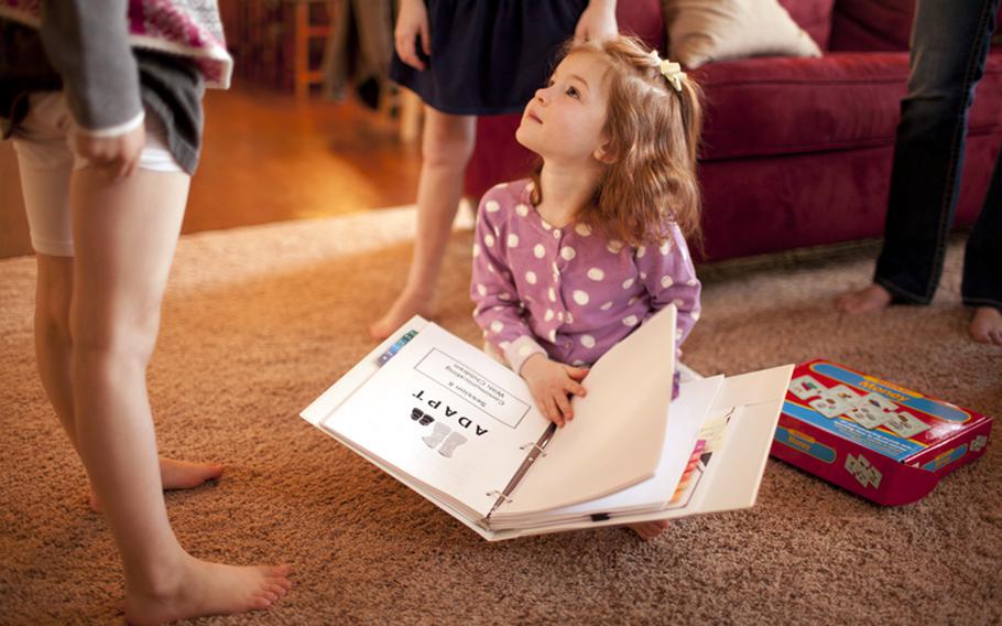 Both John and Mora Thomas of Lakeville, Minnesota, participated in the ADAPT program after John's return from deployment, and said the program gave them valuable parenting skills to use with their daughters, Claire, 4, seated, Isabella, 6, left, and Sophie, 9, after John returned from his deployment. Claire was plays with the ADAPT program binder at the family's home in Lakeville, on Wednesday, March 28. 2012.