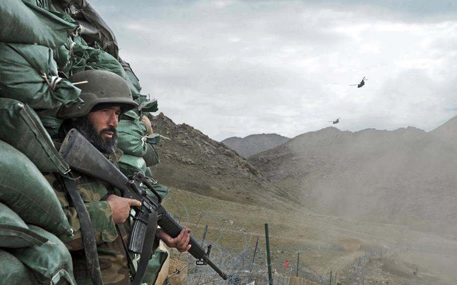 An Afghan National Army soldier stands in a guard tower as American helicopters fly away from Combat Outpost Mizan in Zabul Province, Afghanistan, March 27, 2012.