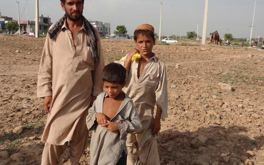 Rangeen (who goes by only one name), 28, an Afghan refugee, with his son, Noor Agha, 7, in front, and another boy, stand by the main road near Sorang Abadi village, just outside Islamabad, Pakistan.