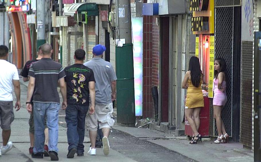 Filipino women stand in the doorway of a juicy bar in The Ville, just outside Camp Casey in South Korea, as soldiers walk by in July, 2009. U.S. Forces Korea has banned servicemembers from buying drinks for workers in “juicy bars,” which have long been suspected of involvement in prostitution and human trafficking.