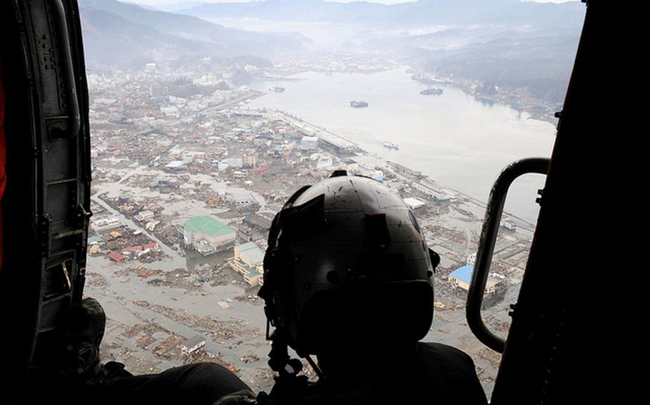 A Navy air crewman surveys the earthquake and tsunami damage from a Black Knight helicopter assigned to the USS Ronald Reagan during Operation Tomodachi, March 20, 2011.